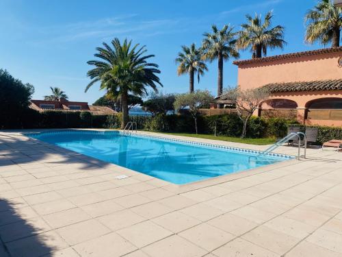 una piscina con palmeras y un edificio en Appartement de la mer, en Sainte-Maxime