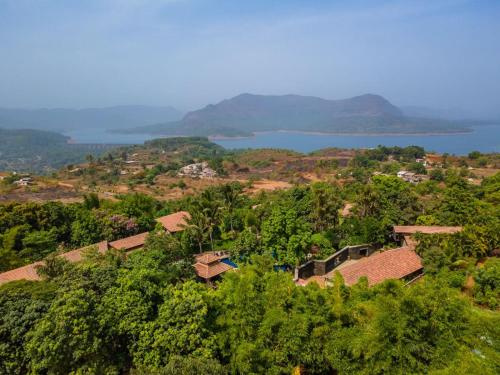 an aerial view of a village with a body of water at Malhar Machi Mountain Resorts in Mulshi