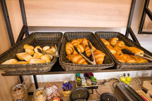 three baskets of bread and croissants on a shelf at B&B HOTEL Bordeaux Mérignac Aéroport in Mérignac