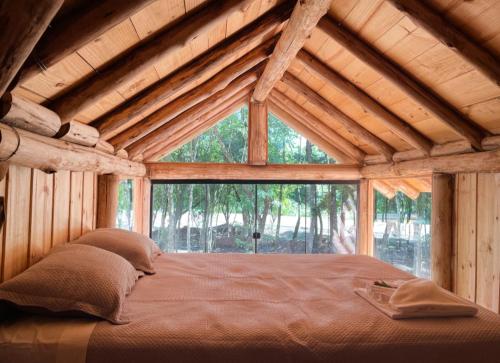uma cama grande num quarto de madeira com uma grande janela em Chalé Refúgio Panorâmico em Canela
