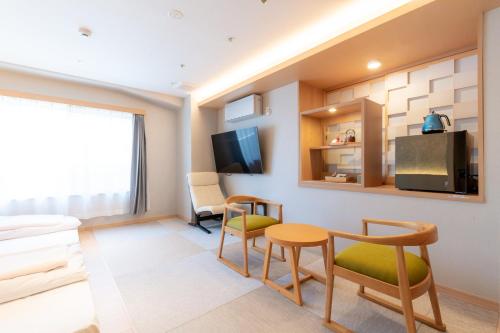 a living room with a couch and a table and chairs at Hotel Isago Kobe in Kobe