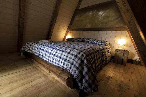 a bed with a checkered blanket in a attic at Orme nel parco - Villaggio Grechi in Tirivolo