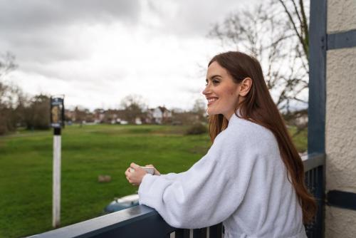 a woman standing on a fence looking at a field at The Crown Inn in Bromley