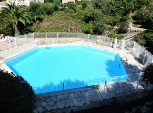 une grande piscine bleue entourée d'une clôture. dans l'établissement Les Coteaux de la Nartelle, à Sainte-Maxime