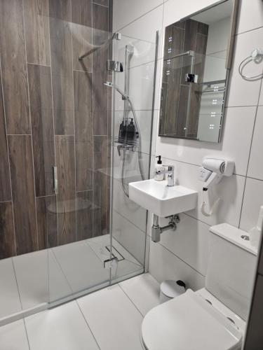 a bathroom with a shower and a sink and a toilet at KORZO SUITES PACEVILLE in St. Julianʼs