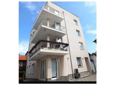 a tall white building with a balcony on a street at Arian's Apartment in Pristina