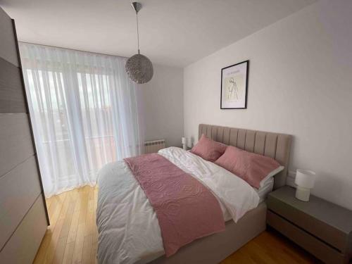 een slaapkamer met een bed met roze en witte lakens bij Arian's Apartment in Pristina