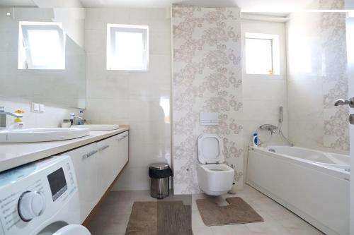 een witte badkamer met een wastafel, een toilet en een bad bij Arian's Apartment in Pristina