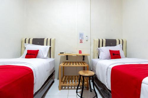 two beds in a small room with red pillows at RedDoorz @ Simpang Pemda Medan in Medan