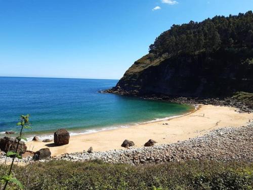 a sandy beach with rocks and the ocean at Casa María VUT 5614 AS in Villaviciosa