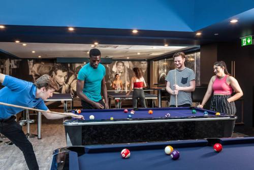 a group of people standing around a pool table at For Students Only Study Inn Talbot Street Nottingham in Nottingham