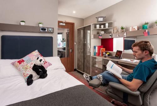 a man sitting in a chair in a bedroom at For Students Only Studios and Ensuite Bedrooms with Shared Kitchen at Talbot Street in Nottingham in Nottingham