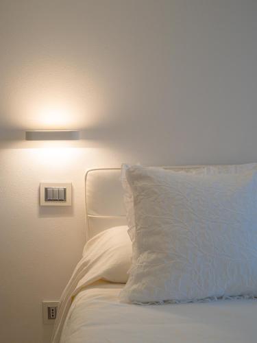 a bed with a white pillow and a light on the wall at White dreams in Portovenere