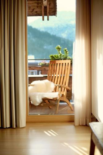 a rocking chair sitting on a balcony with a view at Hotel Post Bezau in Bezau