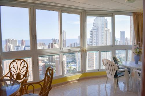 a dining room with large windows and a table and chairs at Ola Azul Sea View Apartment in Benidorm