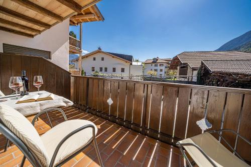 a balcony with chairs and a table with wine glasses at Eco Bnb & Apartments Bründlerhof in Marlengo