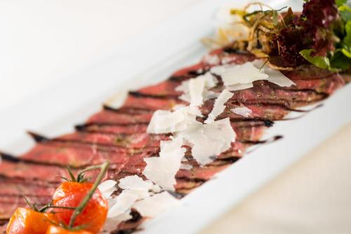 a plate of food with meat and tomatoes on it at Hotel & Restaurant Waldschloss in Passau