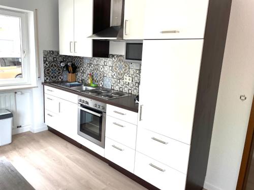 a kitchen with white cabinets and a stove top oven at Weststadt Apartment in Baden-Baden