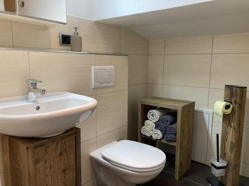 ein Badezimmer mit einem weißen Waschbecken und einem WC in der Unterkunft Ferienwohnung Bergtraum in Sankt Ulrich am Pillersee