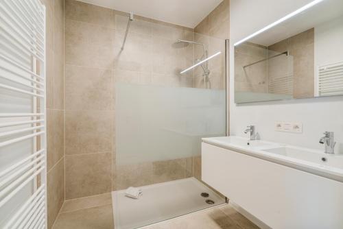 een witte badkamer met een wastafel en een douche bij -The One- verbazingwekkend nieuwbouwapp zeezicht in Blankenberge