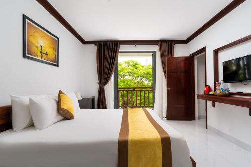 a bedroom with a large bed and a balcony at Haemer Villa Hoi An in Hoi An