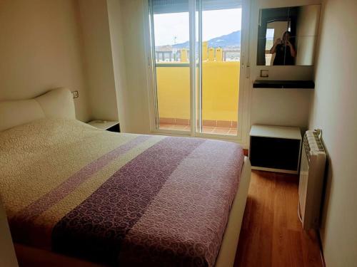 een slaapkamer met een bed en een raam met een persoon die een foto neemt bij Lomas del Mar 5 Magnifique appart -piscine chauffée , paddle, clim, Vue panoramique in Playas de Vera