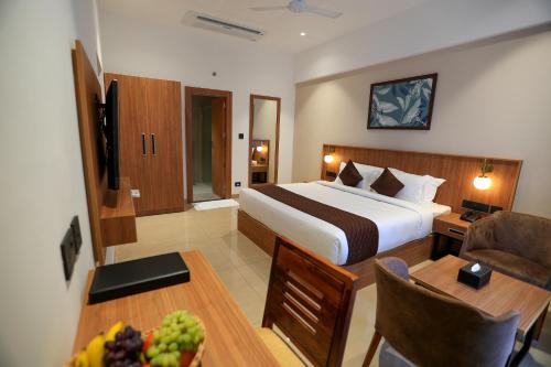 a hotel room with a bed and a table with a bowl of fruit at Hotel Saffron Wayanad in Sultan Bathery