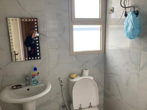 un uomo che scatta una foto a un bagno con wc e lavandino di Maison sur plage ad Al Ḩammām