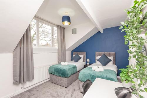 two beds in a room with blue walls at Leeds 4-Bed House - Sleeps 9 Free Parking & WiFi in Leeds