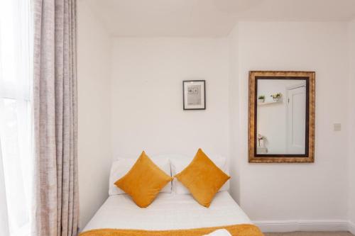 a white couch with two pillows and a mirror at Leeds 4-Bed House - Sleeps 9 Free Parking & WiFi in Leeds
