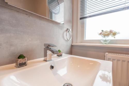 a white sink in a bathroom with a window at Leeds 4-Bed House - Sleeps 9 Free Parking & WiFi in Leeds