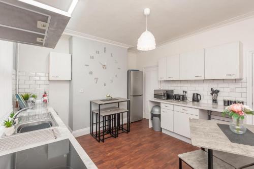 a kitchen with white cabinets and a counter top at Leeds 4-Bed House - Sleeps 9 Free Parking & WiFi in Leeds