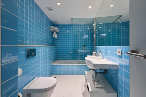 a blue tiled bathroom with a toilet and a sink at Catalonia Avinyo in Barcelona