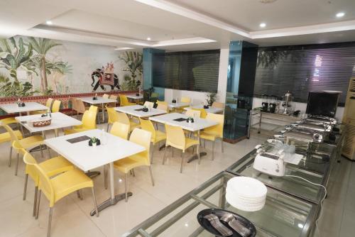 a restaurant with white tables and yellow chairs at Marigold At Nest in Gachibowli