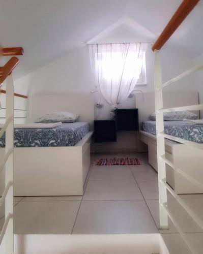 two beds in a room with white walls at Apartmani Vrančić - Sea View & Free Parking in Mandre
