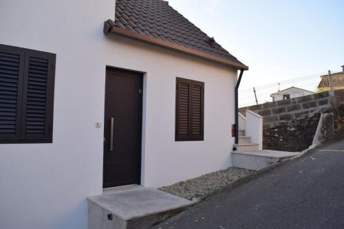 a white house with a black door and a street at Casa Cuartel in Redondela