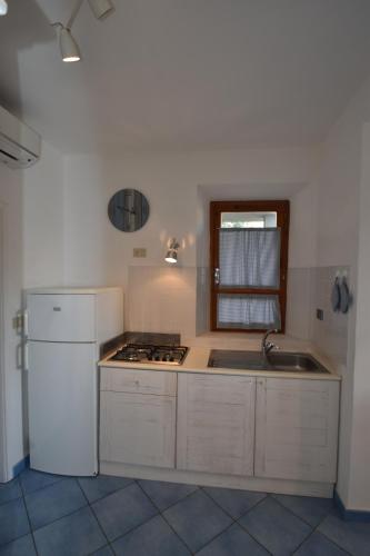 a kitchen with a white refrigerator and a sink at Appartamento Cavoli - Vista mare con terrazza, clima e posto auto in Cavoli