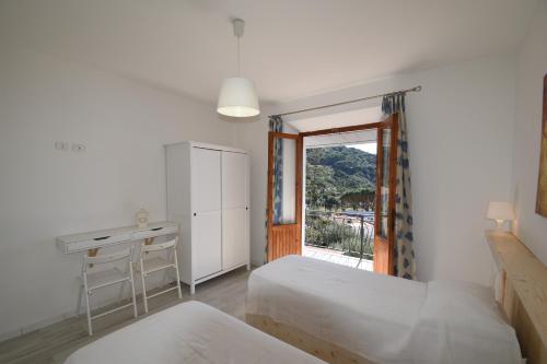 a bedroom with two beds and a desk and a window at Appartamento Cavoli - Vista mare con terrazza, clima e posto auto in Cavoli