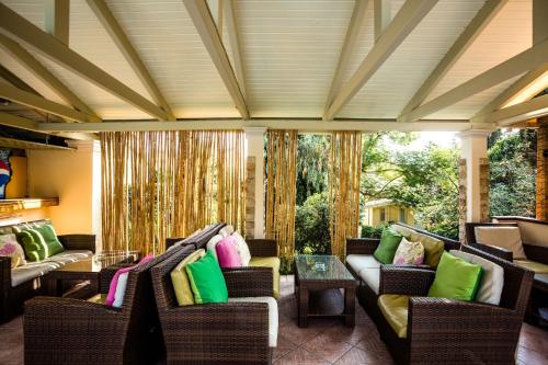 a screened porch with wicker chairs with colorful pillows at Spiti Prifti Apartments in Gouvia