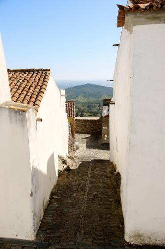 an alley between two white buildings with mountains in the background at Dom Nuno - Turismo de Habitacao in Monsaraz