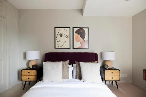 a bedroom with a bed with two lamps and two pictures on the wall at The City of London Secret - Classy 1BDR Flat in London