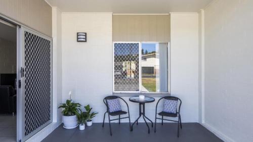 a porch with two chairs and a table and a window at Sunnyvale 2 - Pet Friendly in Yamba