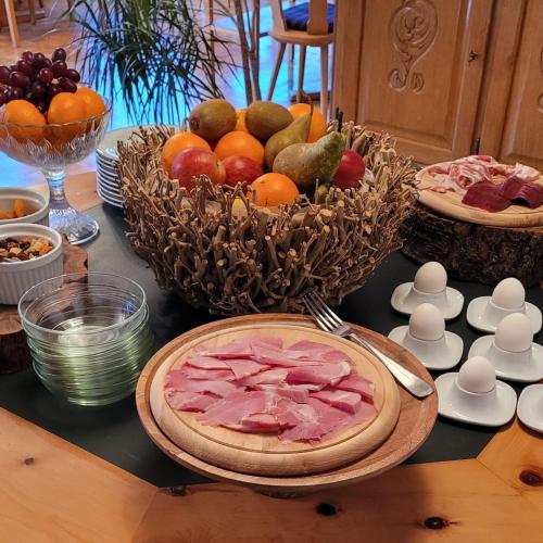 a table with a plate of meat and a bowl of fruit at Alpina Boutique Hotel Interlaken - Ringgenberg - Adults only ! in Ringgenberg