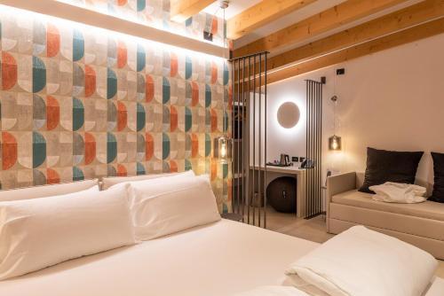 una camera con un letto bianco e un divano di Relais Limonaia - Suites & Garden SPA a Torri del Benaco