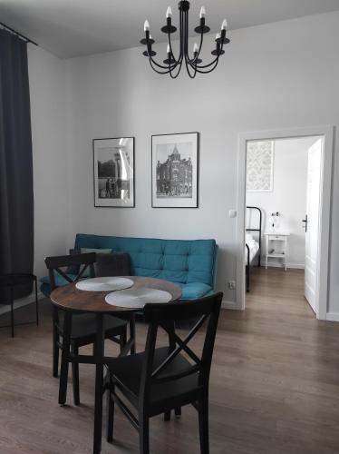 a living room with a blue couch and a table and chairs at Pistacjowy - Apartamenty Smart Projekt in Tarnów