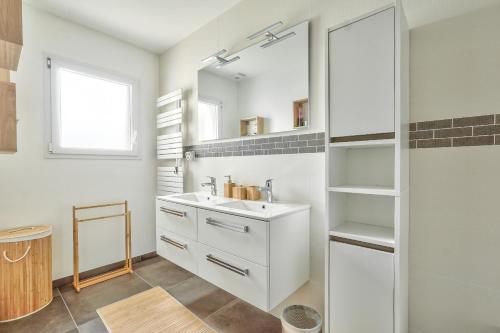 een witte badkamer met een wastafel en een spiegel bij Vacances et detente a la Tranche-sur-Mer in La Tranche-sur-Mer