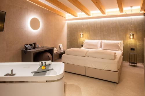 1 dormitorio con cama, lavabo y bañera en Relais Limonaia - Suites & Garden SPA, en Torri del Benaco