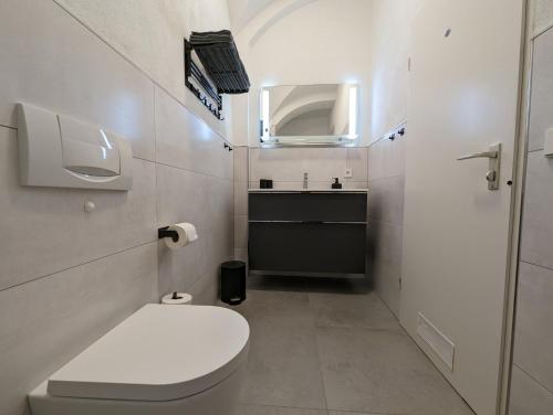 a white bathroom with a toilet and a sink at Im Alten Gefängnis in Überlingen