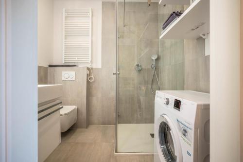 uma casa de banho com uma máquina de lavar roupa e um chuveiro em Suite Perlago em Tignale