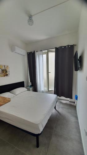 1 dormitorio con cama blanca y ventana en FAGICAMERA, en Olbia